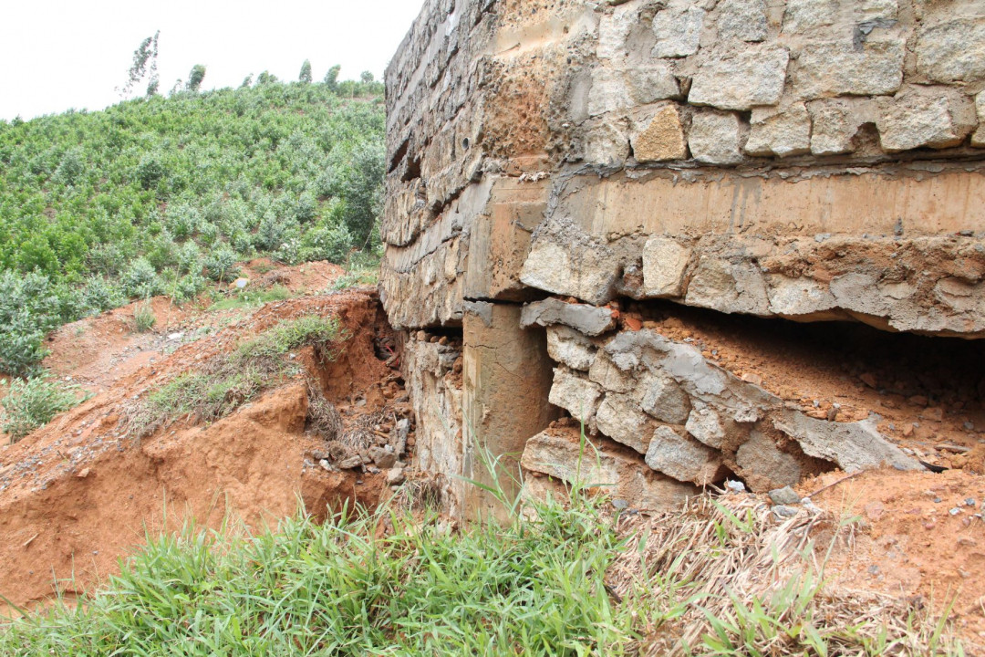 Khu vực bờ kè của đài tưởng niệm bị nước sói mòn, nứt toác lộ ra chân móng.