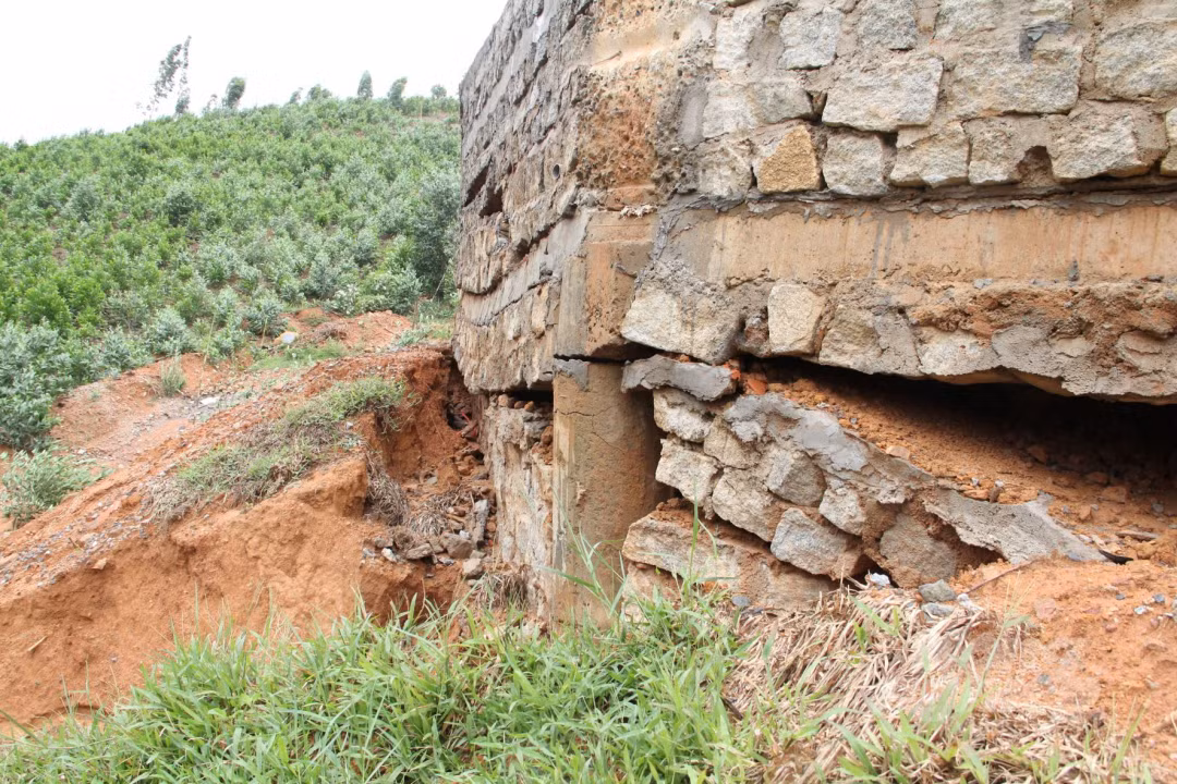 Khu vực bờ kè của đài tưởng niệm bị nước sói mòn, nứt toác lộ ra chân móng.