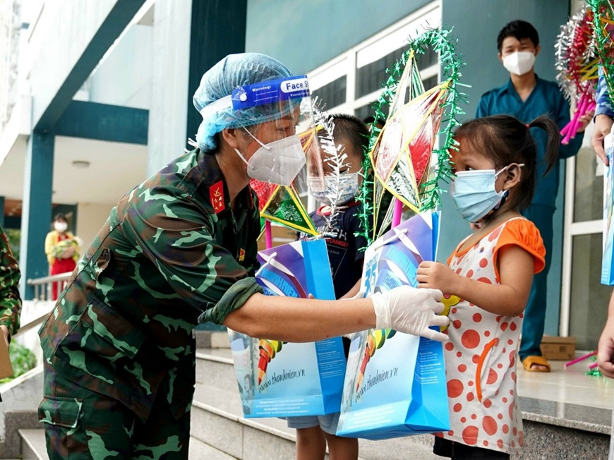 Đại úy QNCN Vũ Thị Hậu, công tác ở Bệnh viện Quân y 105 (Tổng cục Hậu cần), thực hiện nhiệm vụ phòng, chống dịch tại Bệnh viện dã chiến số 5D (Bình Dương) từ ngày 1/8. (Ảnh: Đại úy QNCN Vũ Thị Hậu tặng quà cho các em nhỏ đang điều trị tại Bệnh viện dã chiến số 5D - Báo QĐND)