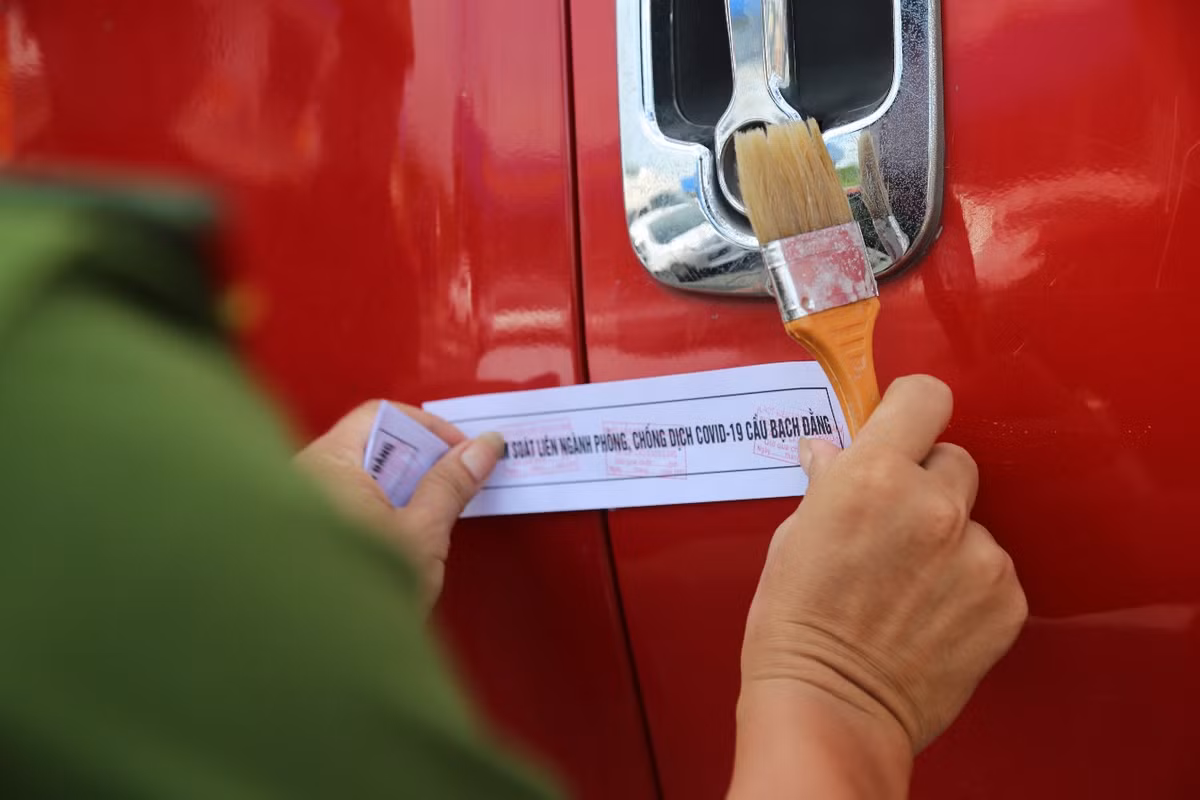 Lực lượng chức năng dán tem niêm phong ca bin xe chở hàng hóa khi đi qua chốt kiểm dịch BOT cầu Bạch Đằng, các xe chở hàng hóa chỉ được dừng, đỗ khi giao hàng ở điểm giao hàng và tiếp nhiên liệu..