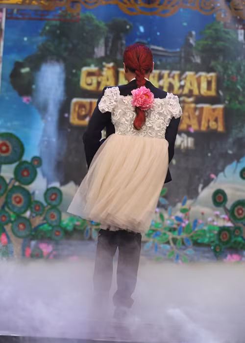 Công Lý diện trang phục đầy nam tính ở phía trước nhưng lại điệu đà ở đằng sau với váy công chúa và tóc tết cài hoa. (Ảnh: Zing)