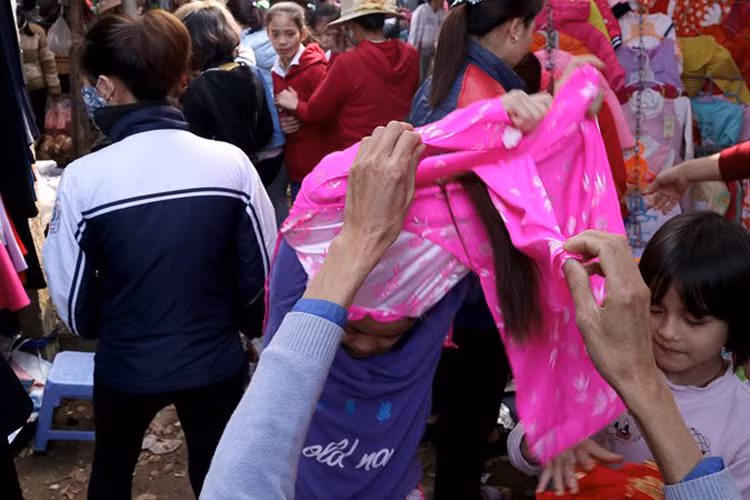 Một bé gái đang ướm thử chiếc áo dài diện Tết.