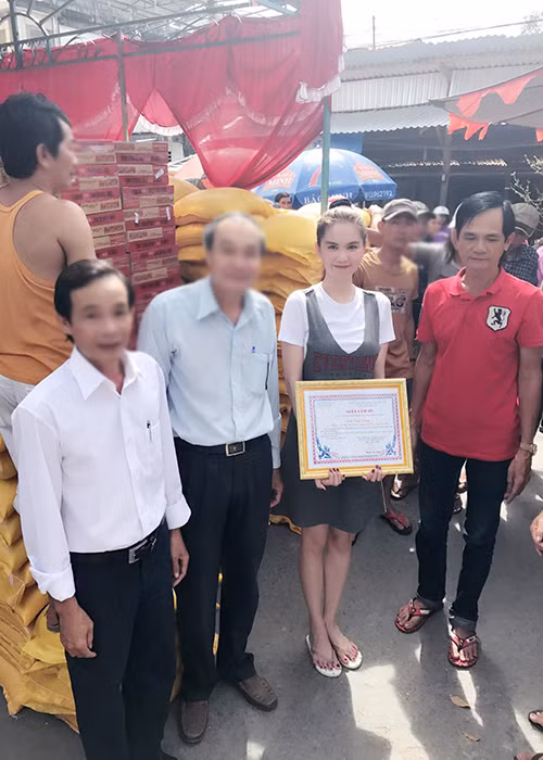 Vẫn như mọi lần đi làm từ thiện, Ngọc Trinh ăn diện giản dị. Trong lần phát gạo mới nhất, bố của cô (áo đỏ) cũng hỗ trợ. (Ảnh: Facebook nhân vật)