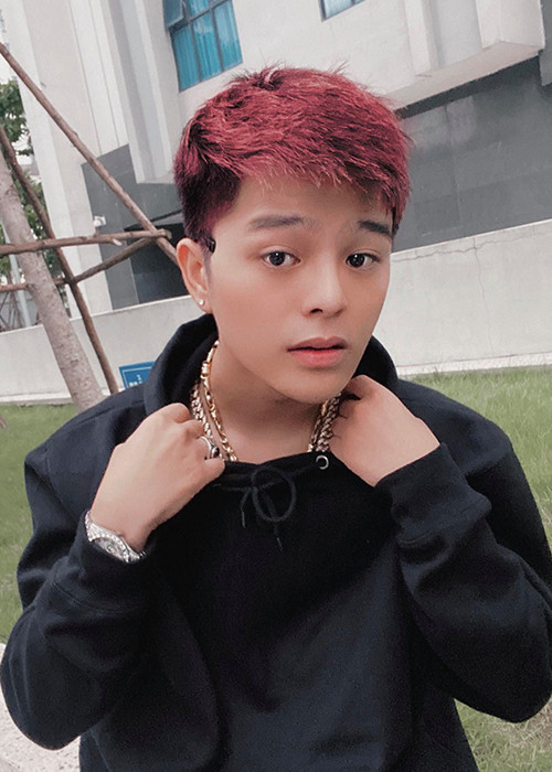 Nam ca sĩ sinh năm 2001 nhuộm tóc, xỏ khuyên tai, khuyên miệng, ăn mặc bụi bặm.