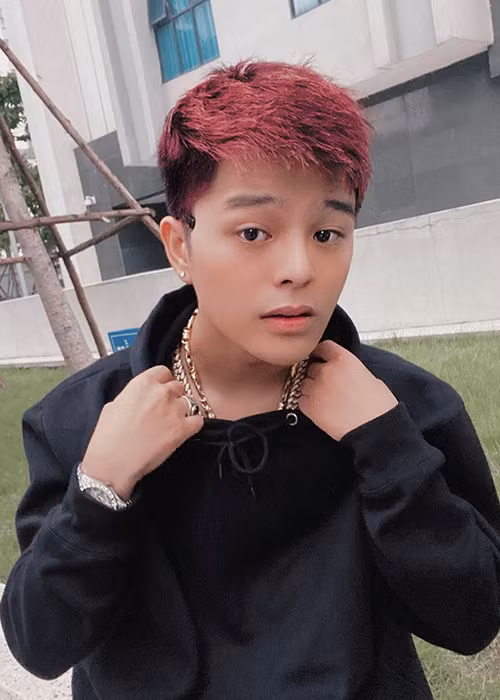 Nam ca sĩ sinh năm 2001 nhuộm tóc, xỏ khuyên tai, khuyên miệng, ăn mặc bụi bặm.