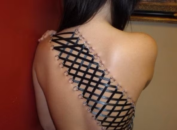 Xăm mình không đủ thỏa mãn, cô gái trẻ này đeo khuyên cả phần lưng và xỏ dây, đan chéo theo sở thích quái dị của mình. (Nguồn Emgn)