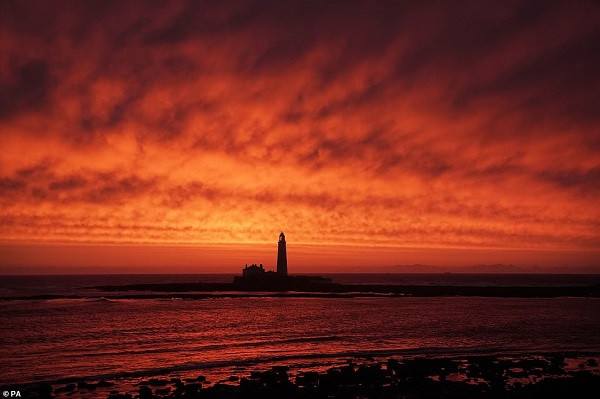 Bầu trời đỏ rực khi mặt trời mọc tại Ngọn hải đăng St. Mary ở thị trấn Whitley Bay, hạt Tyne and Wear. Ảnh: PA