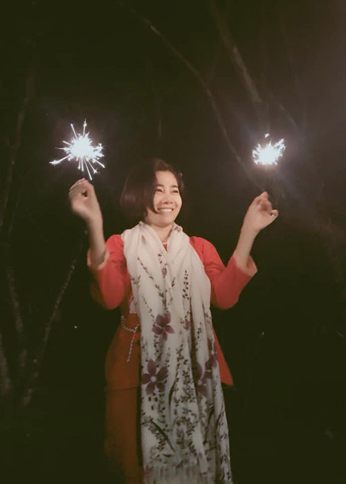 Hình ảnh Mai Phương nở nụ cười, tay cầm pháo bông.