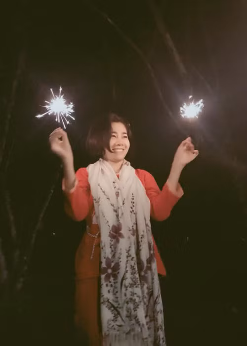 Hình ảnh Mai Phương nở nụ cười, tay cầm pháo bông.