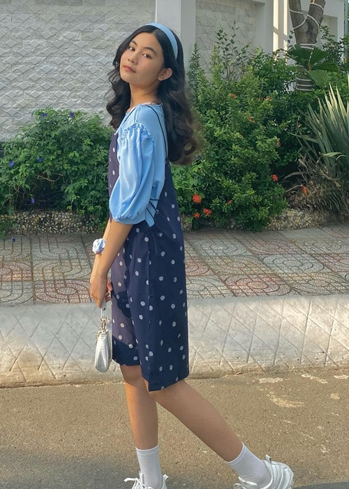 Hạt Dẻ sành điệu với combo váy yếm, áo phông tay phồng, túi xách kẹp nách, giày thể thao.