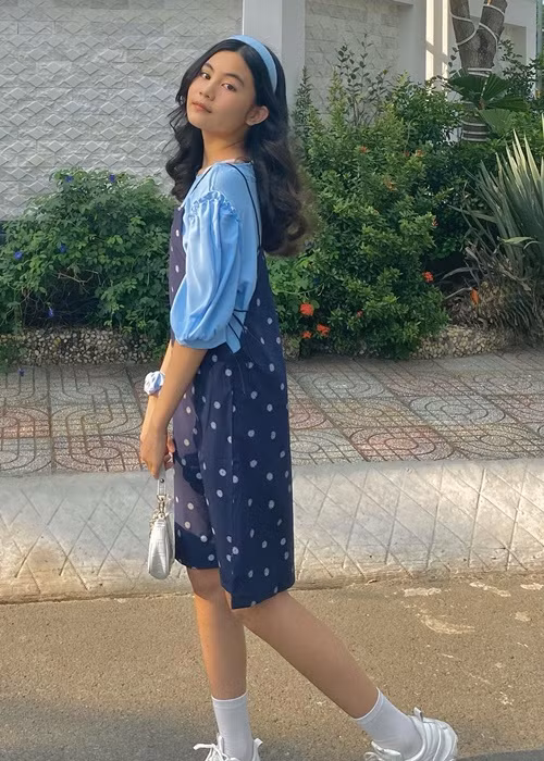 Hạt Dẻ sành điệu với combo váy yếm, áo phông tay phồng, túi xách kẹp nách, giày thể thao.