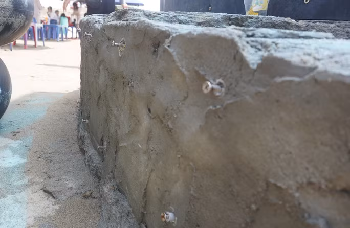 Sau khi các bàn tay hoàn thành, các tấm cao su ốp vào trụ các bàn tay đã bị sóng đánh bong tróc, trơ đinh vít tiềm ẩn nguy hiểm cho du khách. (Ảnh: Người lao động).