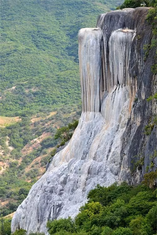 13. Thác Hierve el Agua, Mexico. Hierve el Agua là một vách đá tự nhiên ở bang Oaxaca và trông giống như một thác nước đang chảy. Khu vực này bao gồm 2 vách đá có độ cao 50 và 90m tính từ thung lũng phía dưới. Vách đá được hình thành bởi một lượng nhỏ nước bão hòa cacbonat canxi chảy ra từ các khe nứt. Nước ở đây có nhiệt độ trung bình là 22 đến 27 độ C. Khi nước chảy xuống bề mặt đá, nó tạo thành những nhũ đá lớn như trong hang động. Dòng chảy của nước ở đây thay đổi theo mùa và mạnh nhất là vào mùa xuân. Nước ở đây có hàm lượng khoáng chất cao và có tác dụng chữa bệnh rất tốt.