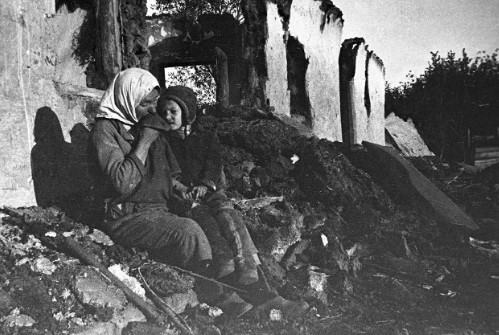 Người phụ nữ và con nhỏ ngồi trước ngôi nhà của mình bị phá hủy do bom đạn chiến tranh. Mời độc giả xem video: Bảo tàng đồ cũ thời Liên Xô. Nguồn: VTC14.