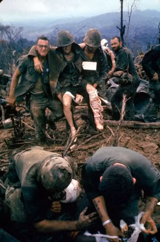 Lính Mỹ dầm mình trong bùn đất bên cạnh là những người đồng đội bị thương với vết máu ở khắp người.