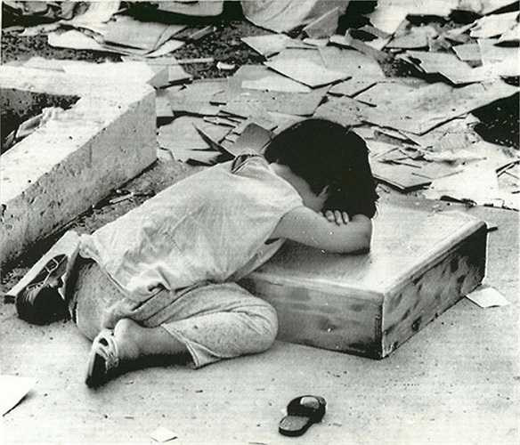 Hình ảnh nhói lòng bé gái ngủ gục ngay bên cạnh đống đổ nát của một tòa nhà bị phá hủy bởi bom đạn chiến tranh ở Kontum tháng 5/1972.