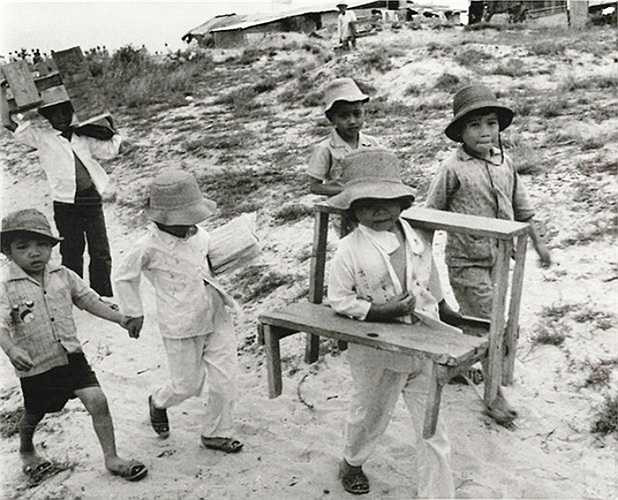 Một số học sinh mang sách vở, bàn ghế đến lớp học ngoài trời ở Quảng Trị ngày 24/9/1973.