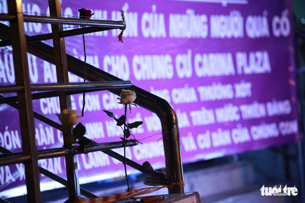 Dù lễ cầu nguyện chỉ diễn ra hơn 1 giờ, nhưng người đến dự ngày càng đông. Không chỉ cầu nguyện cho các nạn nhân xấu số, họ còn cầu nguyện cho những người còn điều trị trong các bệnh viện mau chóng hồi phục. Ảnh: Những bông hoa hồng trắng được cắm trước chung cư Carina để tưởng nhớ những người đã khuất.