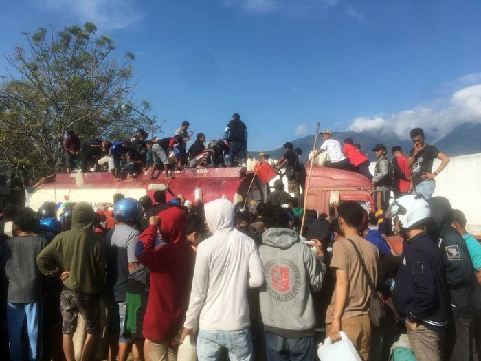 Người dân thành phố Palu bất chấp nguy hiểm tụ tập rút xăng từ một xe bồn bị bỏ lại sau đợt thiên tai ngày 28/9. Ảnh: AP.