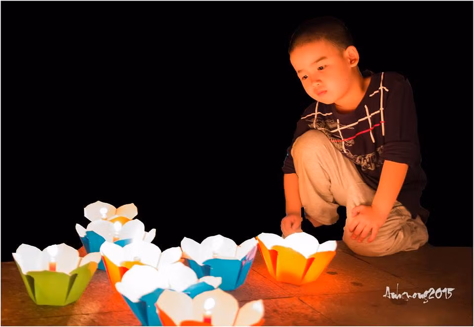 Đứa trẻ khuôn mặt tươi tắn, rạng ngời bên ánh đèn hoa đăng lung linh.