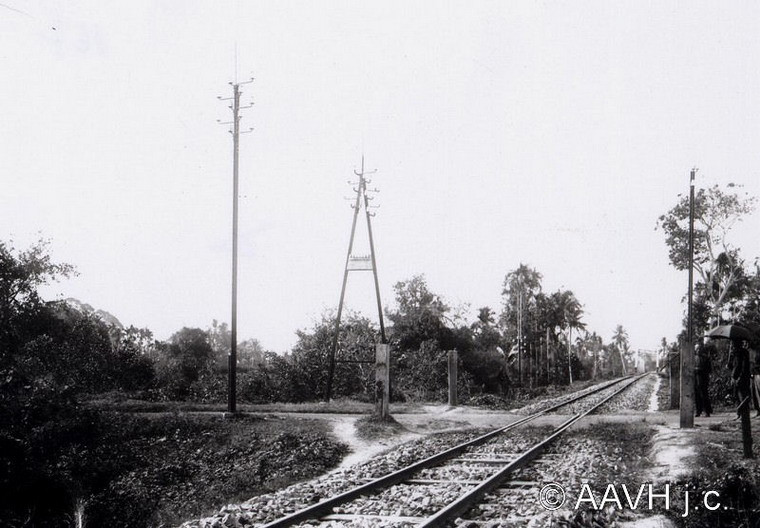 Một điểm giao cắt đường bộ và đường sắt. Dọc theo tuyến đường sắt là các cột điện báo, xương sống của ngành thư tín Việt Nam thập niên đầu thế kỷ 20.