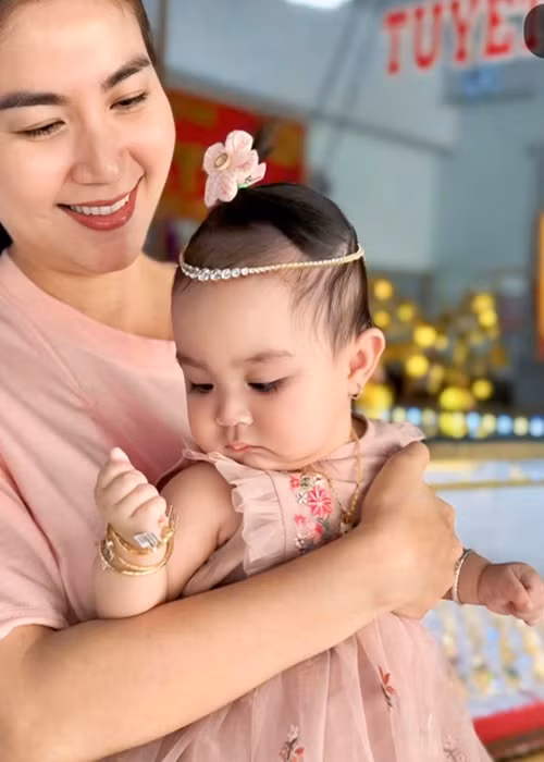 Kha Ly khoe ảnh hài hước của chồng con ngày vía Thần Tài. "Mùng 10 vía Thần Tài, con với ba con không có gì ngoài vàng đeo đỏ người, hai ba con thương chúc cho ông bà cô chú làm ăn phát tài, vàng đeo đỏ tay nha. Nhưng con nói nhỏ cô chú nghe ba con đeo vàng giả đó", Kha Ly chia sẻ. Ảnh: FB Kha Ly.