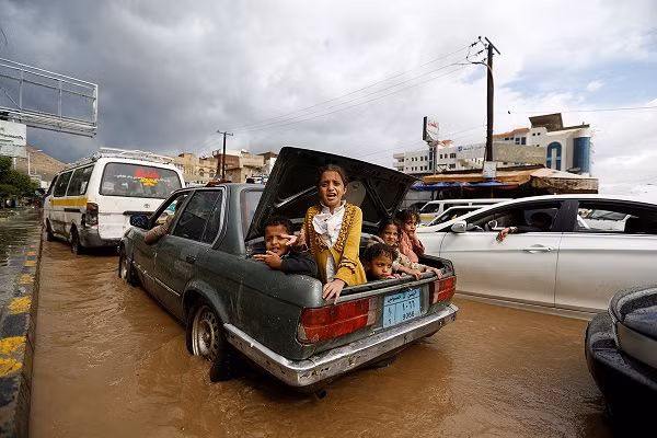 Những đứa trẻ ngồi trong cốp ô tô di chuyển qua con đường ngập lụt ở Sanaa.