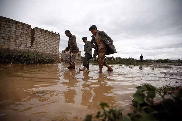 Người dân Yemen lội qua con đường ngập nước ở Sanaa.