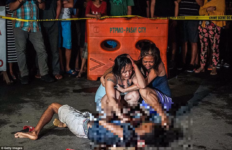 Hai người phụ nữ gào khóc sau khi người thân của họ trúng đạn trên đường phố Manila hôm 23/7.