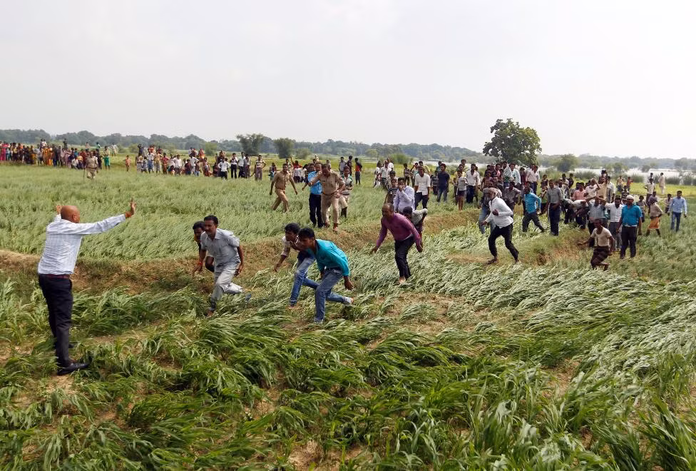 Đông đảo người dân bị ảnh hưởng trong đợt mưa lũ đổ xô tới nhận thực phẩm cứu trợ được một chiếc trực thăng của Không quân Ấn Độ mang tới ở vùng ngoại ô Allahabad ngày 25/8.