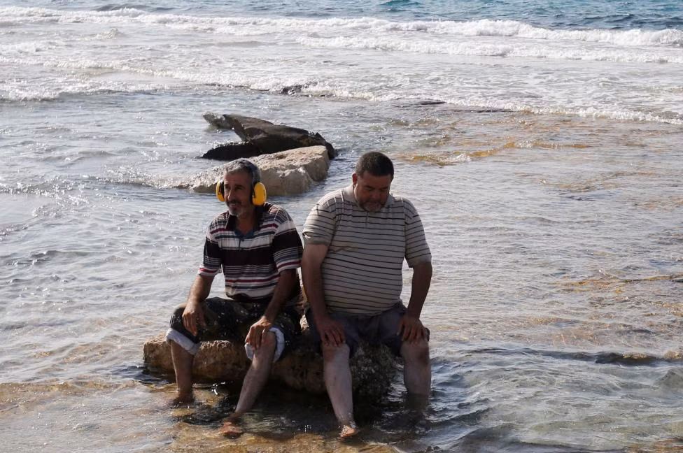 Hai chiến binh của lực lượng Libya ngồi nghỉ trên bãi biển ở Sirte.