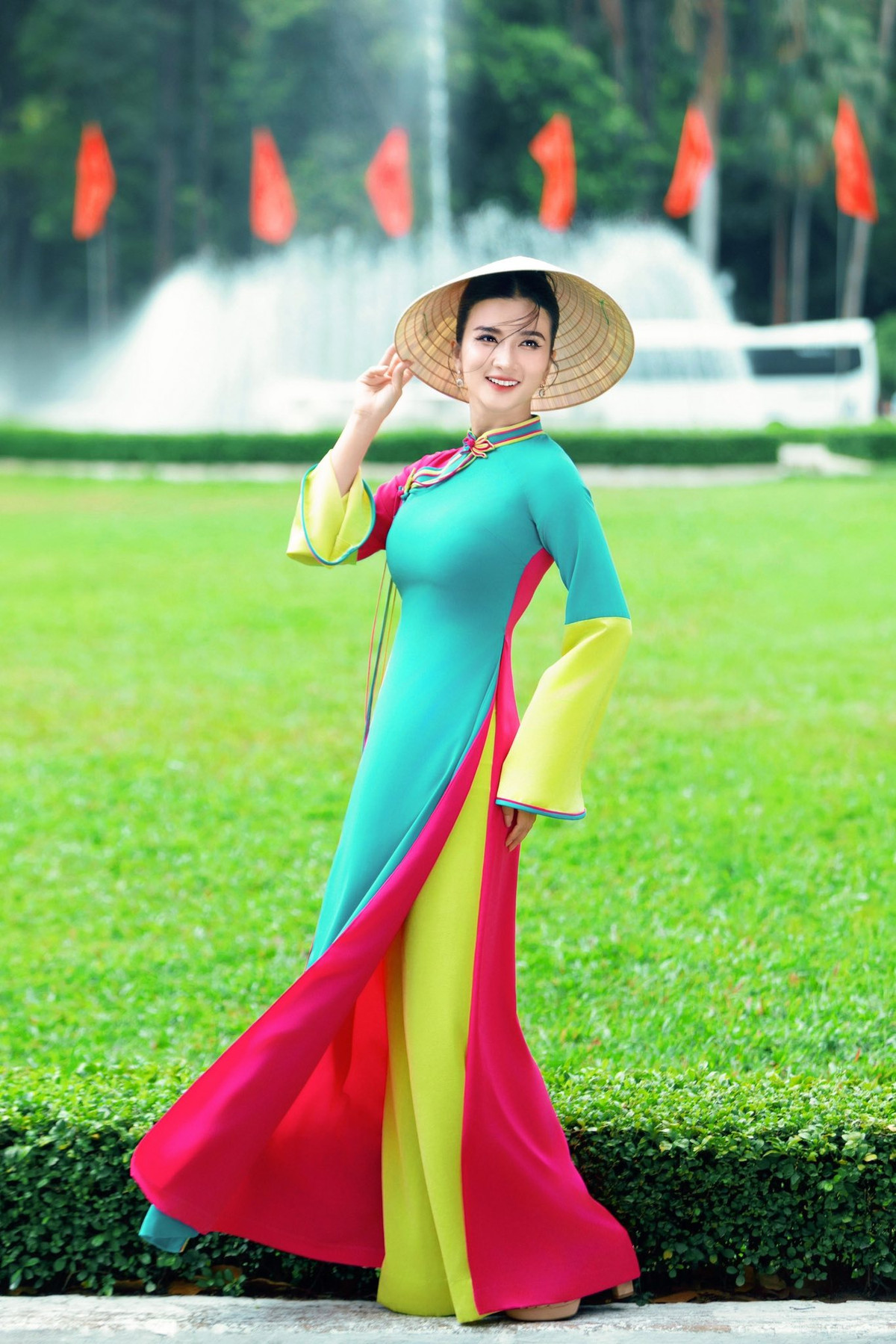 NSƯT Kim Tuyến duyên dáng trong áo dài đa sắc và nón lá, tạo dáng trước bãi cỏ ở Dinh Độc Lập. Ảnh: FB Kim Tuyen
