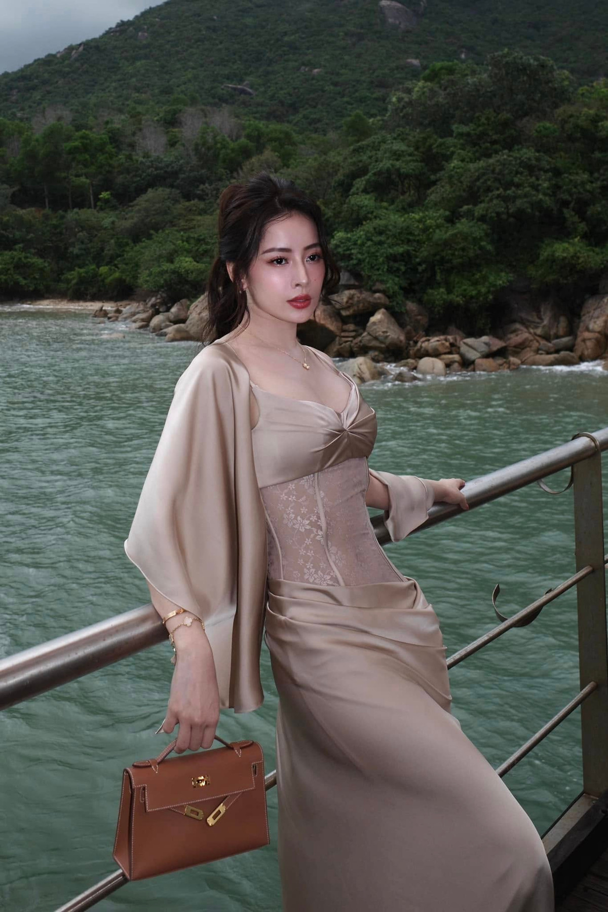  Tin tức sao Việt 12/3: Chi Pu diện váy lụa satin dài thướt tha có điểm nhấn là phần eo corset ren trong đám cưới của bạn thân Salim. Cô phối thêm khăn lụa cùng túi Hermès Kelly màu nâu da bò, trị giá hàng trăm triệu đồng. Ảnh: FB Chi Pu