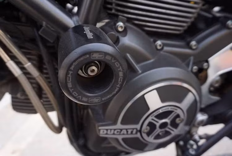 Nằm hai bên khung xe, những cục chống đổ từ hãng Evotech bảo vệ Scrambler khỏi những vết trầy xước trong trường hợp xe bị tai nạn. Thương hiệu Evotech cũng xuất hiện trên tấm chắn bộ chỉnh lưu điện của xe.