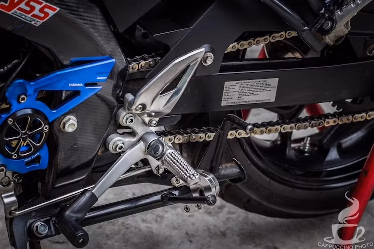 Tư thế ngồi của chiếc xe không chỉ được thay đổi nhờ có bộ ghi-đông mới mà còn nhờ dàn để chân lấy từ Yamaha TFX150. Ngay bên cạnh dàn để chân, bộ khung Deltabox của FZ150i đã được ốp carbon, trong khi mang cá của xe là phụ kiện Yamaha có dạng nhôm CNC tinh xảo.