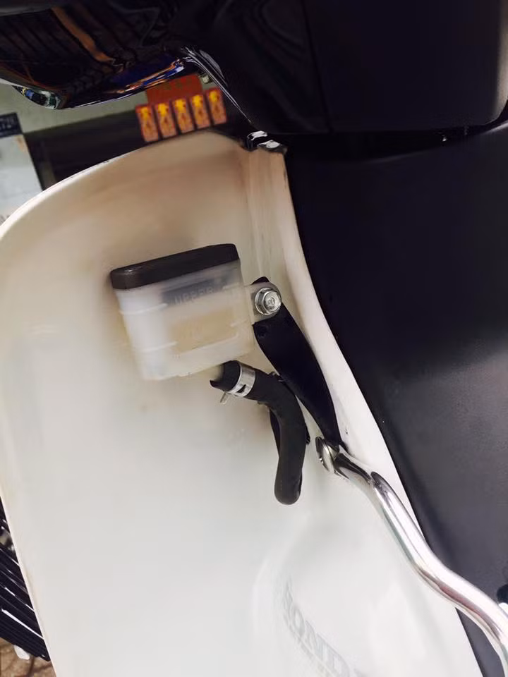 Để không phải khoét lỗ trên phần đầu xe nhằm đặt bình dầu phanh trước, chủ của chiếc Dream Exces này đã lựa chọn giải pháp "giấu" bình dầu sau yếm một cách gọn gàng.