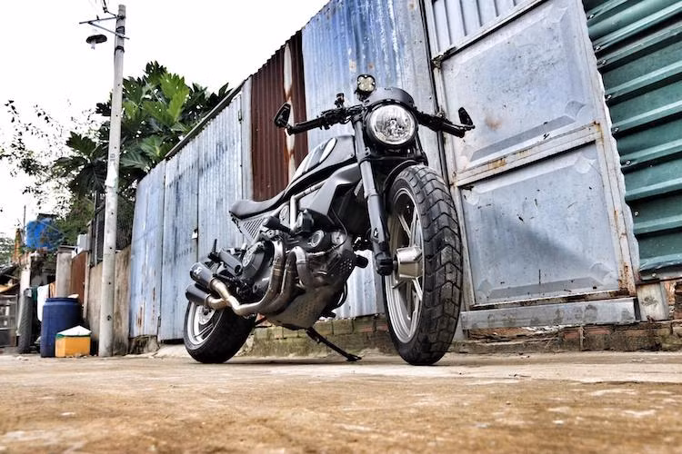 2 bên tay lái của xe là cặp xi-nhan LED đồng thời đóng vai trò là gù xe, đồng thời chủ nhân của chiếc Scrambler cũng đã lựa chọn gương hậu gắn gù CRG gọn gàng hơn cho xe. Nằm ở phía trên đèn pha nguyên bản là tấm cản gió bằng nhôm chính hãng của Ducati với thiết kế đục lỗ góc đầy cá tính.