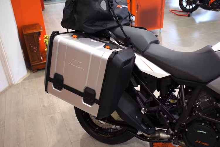 Chiếc KTM 1290 Super Adventure trong bài viết này còn được trang bị sẵn cặp thùng nhôm ở hai bên thân - phụ kiện không thể thiếu trên một chiếc adventure đường dài. Có khả năng tháo rời nhanh, thùng trái của xe có thể thích 42 lít trong khi thùng phải chỉ đạt 31 lít do bị "cắt góc" để nhường chỗ cho ống xả đặt cao của chiếc xe.