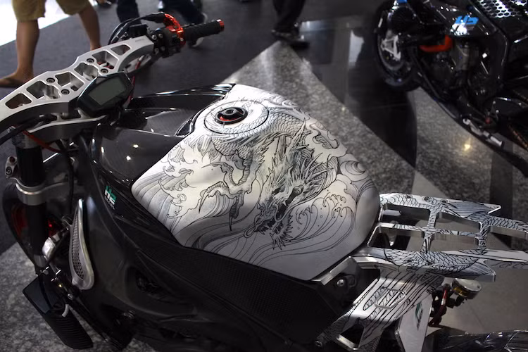 Bình xăng nguyên bản của R1 đã được trang trí lại bằng cách dán decal. Trong đó, nửa trên của bình xăng có decal vân carbon 5D như thật và bên dưới là decal kim loại xước được in hình rồng châu Á.