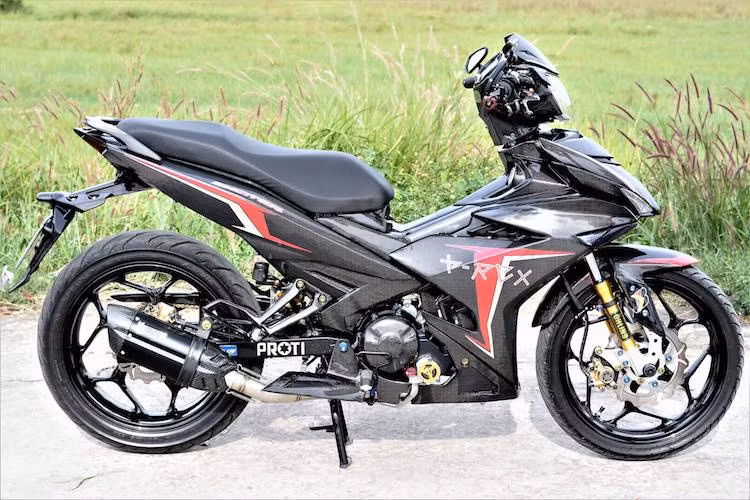 Được độ theo phong cách kiểng quen thuộc, nhưng chiếc Yamaha Exciter 150 của một biker sống tại Sài Gòn này đã gây ấn tượng đặc biệt khi có bộ sợi carbon. Với màu đen cùng với những hoa văn đặc trưng của sợi carbon, chiếc xe đã có ngoại hình cực "cool" như những siêu xe vỏ carbon đặc biệt từ McLaren hay Koenigsegg.