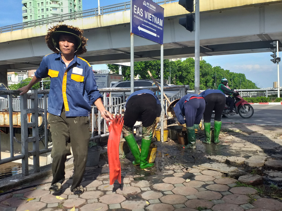 Các công nhân thay nhau xuống dầm mình dưới lòng sông Tô Lịch để nạo vét bùn, đất.