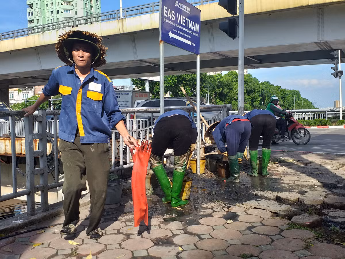 Các công nhân thay nhau xuống dầm mình dưới lòng sông Tô Lịch để nạo vét bùn, đất.
