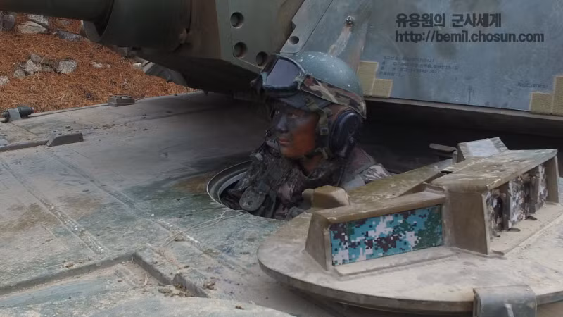 Dù phải ngồi trong xe tăng nhưng nữ quân nhân này vẫn phải bôi một lớp phấn đen lên mặt để hóa trang. Ảnh: Chosun.