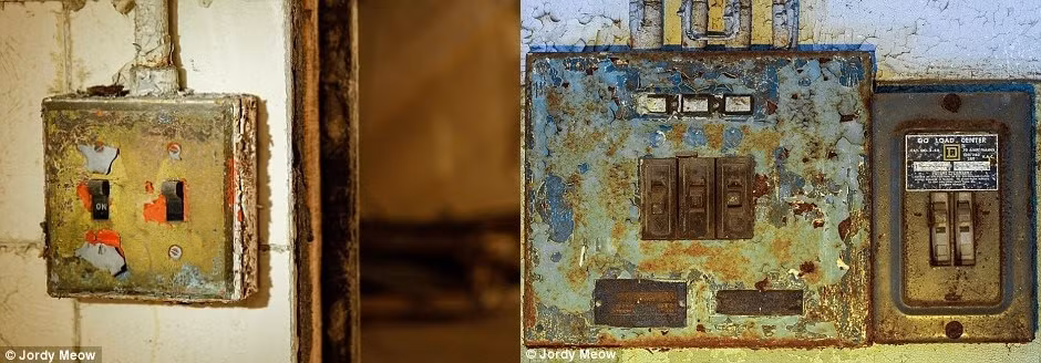 Những khung cửa vênh và công tắc đèn han gỉ được chụp lại bên trong tòa nhà bỏ hoang.