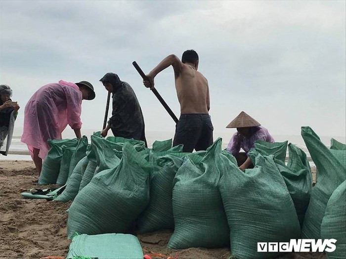 Người dân khẩn trương lấy cát để chặn mái tôn, tường rào, bảo vệ nhà cửa, hàng quán trước bão số 3.