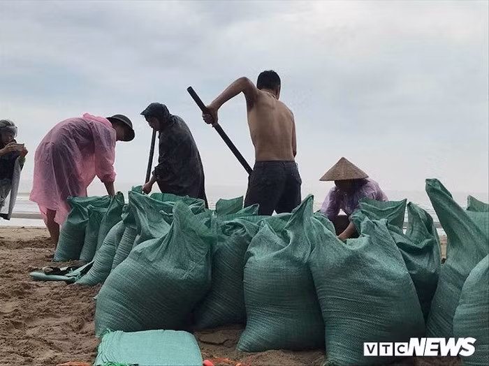 Người dân khẩn trương lấy cát để chặn mái tôn, tường rào, bảo vệ nhà cửa, hàng quán trước bão số 3.