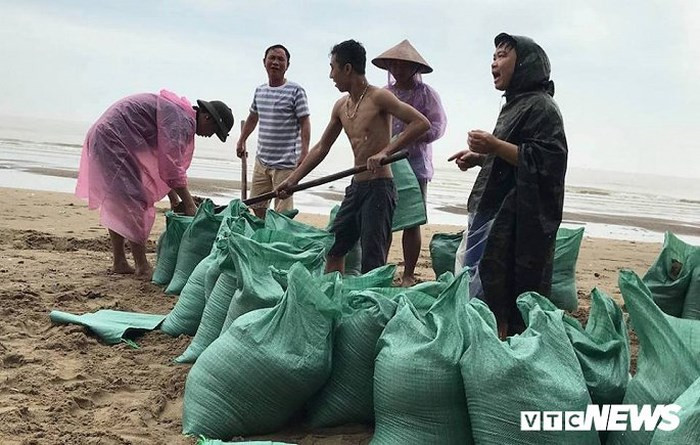 Người dân khẩn trương lấy cát để chặn mái tôn, tường rào, bảo vệ nhà cửa, hàng quán trước bão số 3.