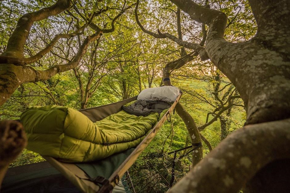 Cắm trại trên đỉnh núi Goodleaf, đảo Wight, Anh: Ngủ trên một chiếc võng, ẩn mình trong những tán cây sồi là trải nghiệm mới trên đảo Wight. Đầu tiên, du khách được hướng dẫn cách di chuyển trên cây, sau đó ăn tối, đốt lửa trại, cuối cùng sẽ leo lên “thuyền cây” của mình và qua đêm. Ảnh: Goodleaf.