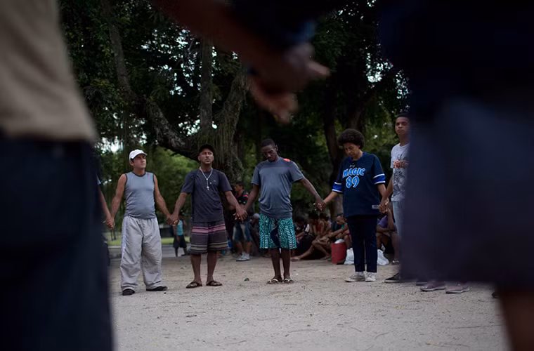 Những người vô gia cư cầu nguyện trước khi nhận bữa sáng được các tình nguyện viên phân phát. Ảnh: AJ.