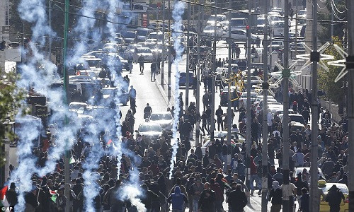 Những người biểu tình Palestine ném đá vào lực lượng an ninh Israel trong khi các binh sĩ Israel dùng hơi cay để giải tán đám đông ở Bethlehem. Các quan chức y tế cho hay, ít nhất 31 người đã bị thương trong các vụ ẩu đả sáng 7/12. Ảnh: Reuters.